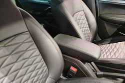 Luxury car interior with quilted leather seats in light gray and black tones, center console visible