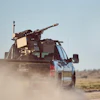 Military-equipped GMC pickup truck driving through dusty desert terrain