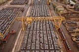 Aerial view of busy shipping port with hundreds of stacked containers, yellow gantry cranes, and cargo handling equipment
