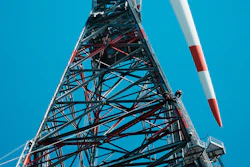 Tall telecommunications tower with red and white striped antenna against clear blue sky