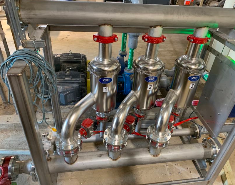 Industrial stainless steel multi-valve manifold system with red handles mounted on frame in workshop
